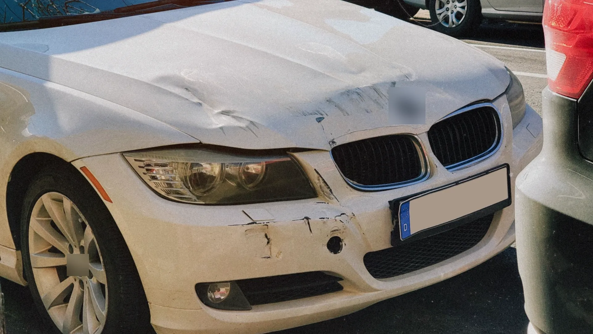 Carro branco com o capô amassado e o para-choque riscado